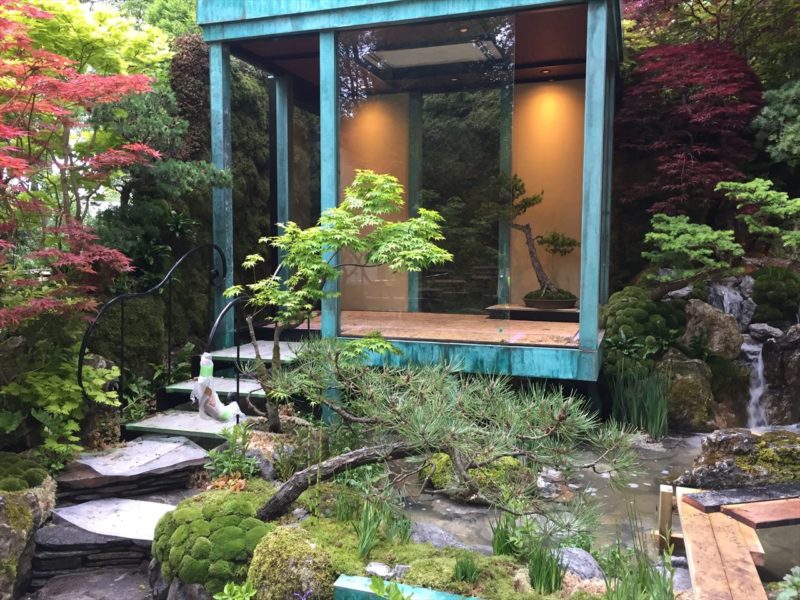 和風の庭の中に建つ明かりがともされた緑青の建物