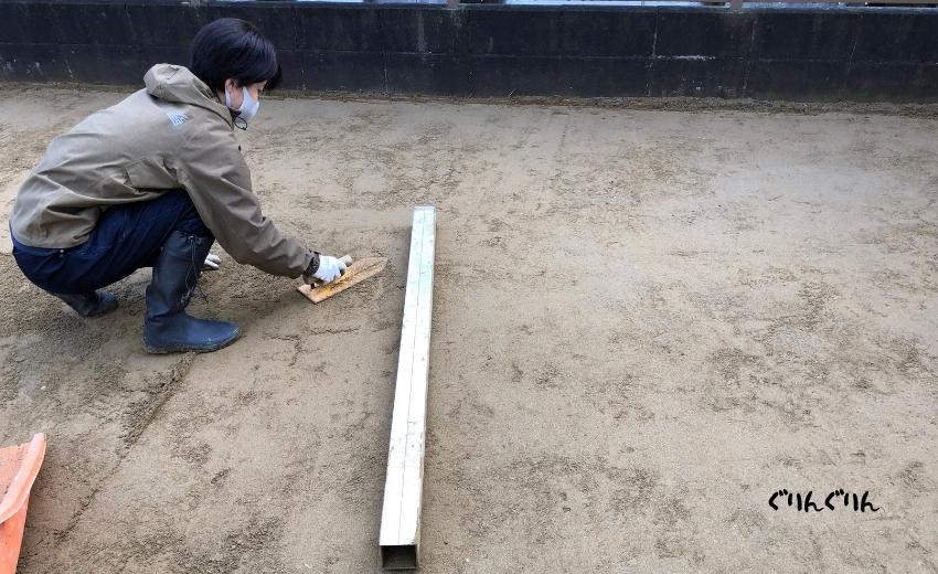 木更津市の人工芝の設置で下地づくりでアルミ棒を使う女性職人さん