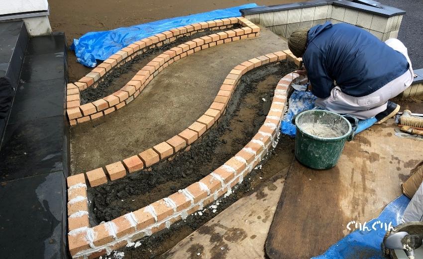木更津市で施工した厳しい曲線のレンガ花壇の目地埋めをする職人さん