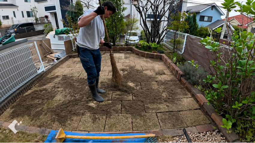 芝生の目地に山砂を入れる作業。手で直接押し込むとしっかり入る