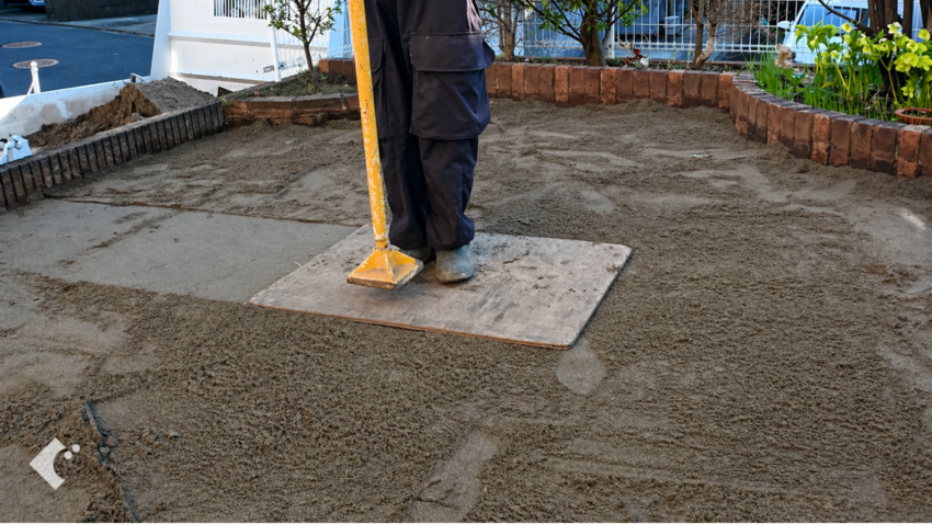 敷いた砂を足で踏み固めて転圧する様子。しっかり固めることで芝生が安定する