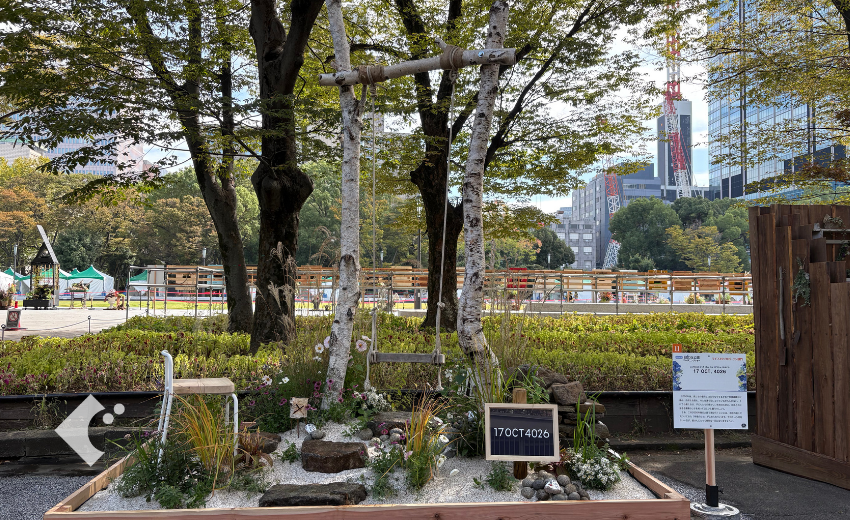 草花のすき間から見える、ロープで吊るした木の座面のブランコ
